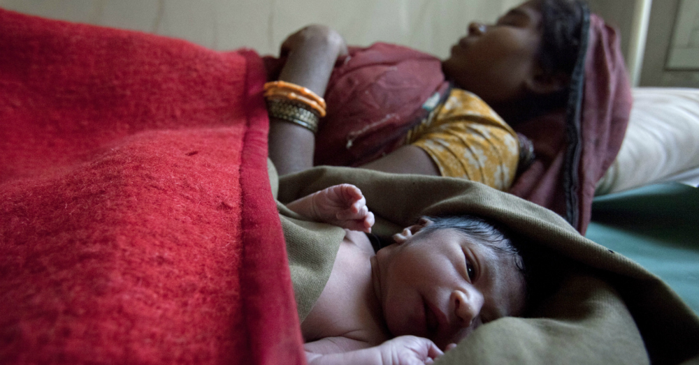 Photo of a woman sleeping with newly born child.